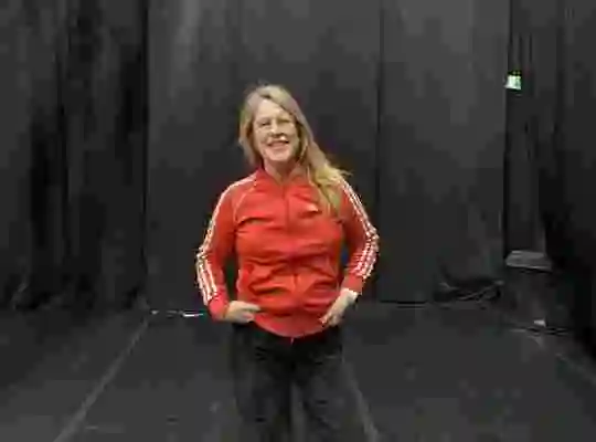 En foto på cirkusartisten Angela Wand i röd tröja i en black box.