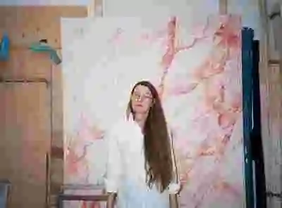 Christine Ödlund står framför en av sina målningar