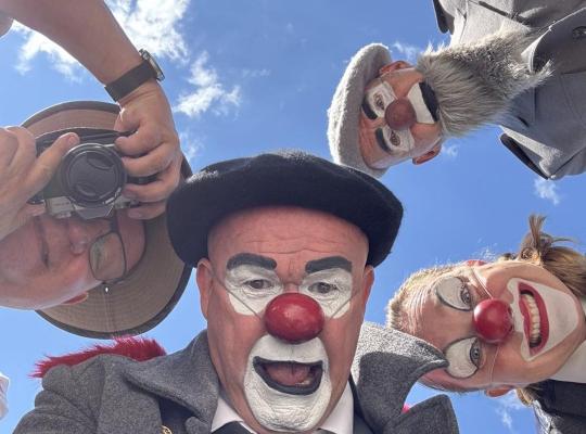 3 clowner och en fotograf tittar in i bilden som är tagen med grodperspektiv.