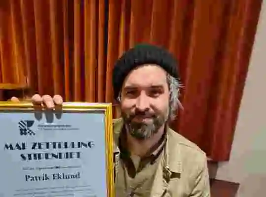 Filmregissören Patrik Eklund håller upp diplomet han fick vid stipendieutdelningen