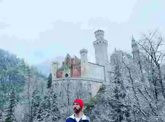 Skådespelaren Olle Sarri i filmen står framför ett slott i vinterlandskap.