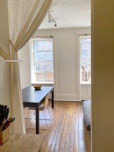 Lägenhetens vardagsrum, köksbord för två, liten futon och två fönster