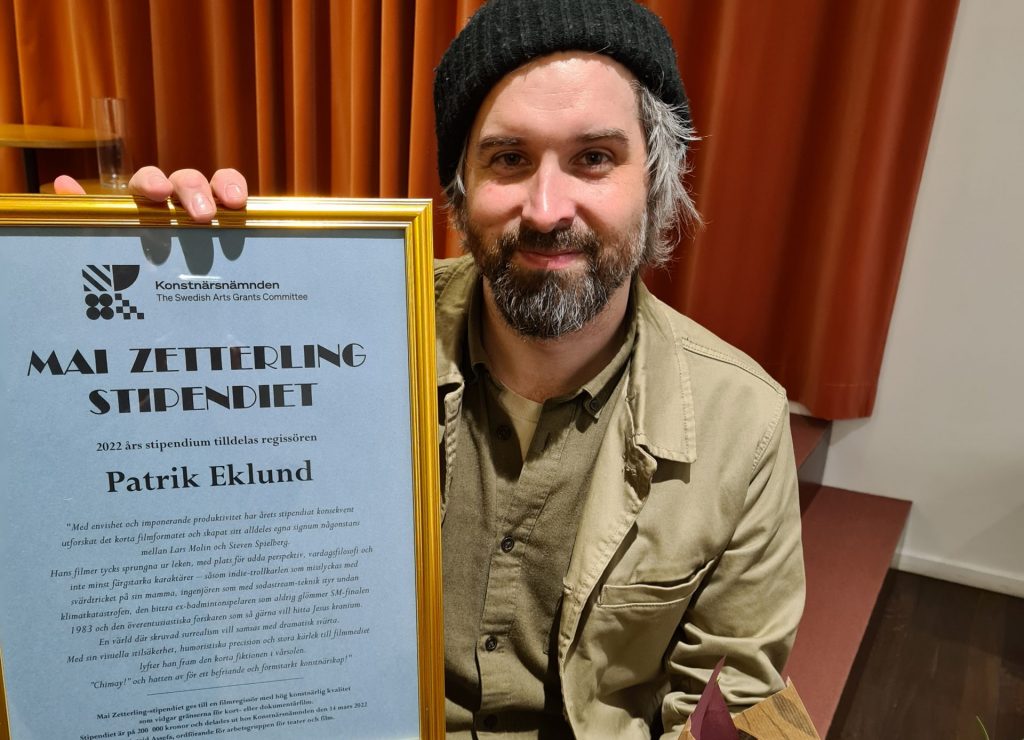 Filmregissören Patrik Eklund håller upp diplomet han fick vid stipendieutdelningen