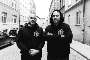 Svartvitt porträtt av två musikproducenter ståendes på en gata