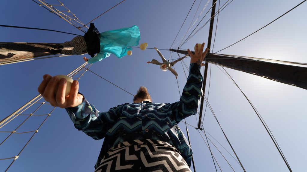 Grodperspektiv på en cirkuskonstnär som jonglerar på en båt