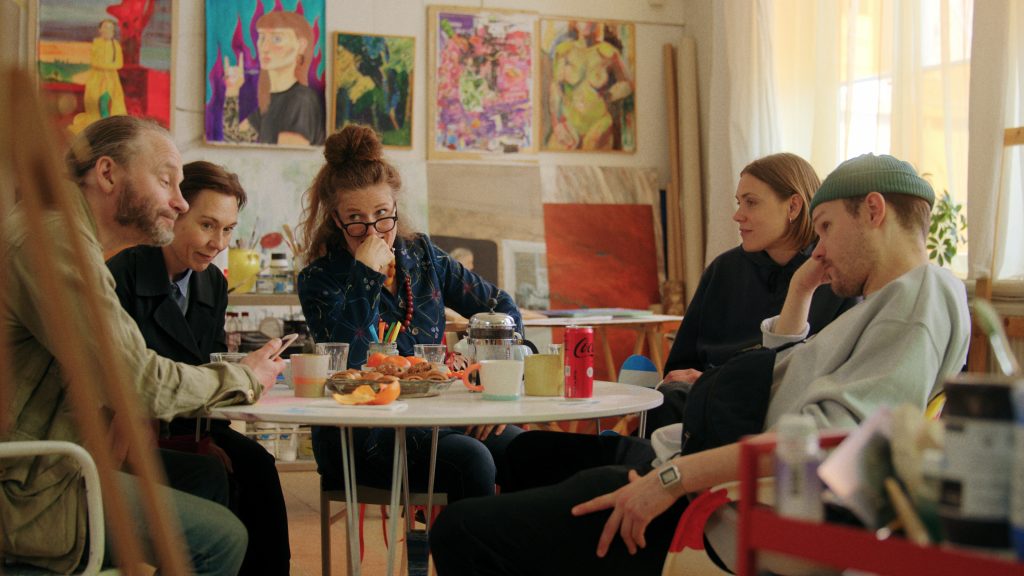 En stillbild från en film där personer sitter runt ett mötesbord.