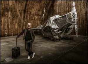 Musikern Jakob Karlzon står i en hangar framför ett flygplan.