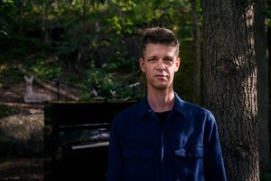 Ett foto på musikkonstnär utomhus framför ett träd.