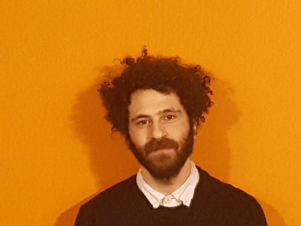 Fotoporträtt av musikkonstnären Wissam Sader framför en orange bakgrund,
