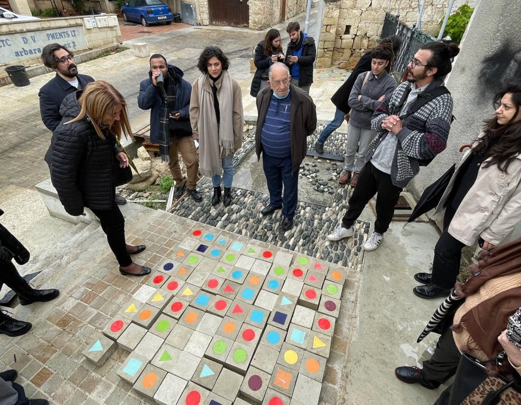 People standing around small blocks of concrete with patterns on the ground