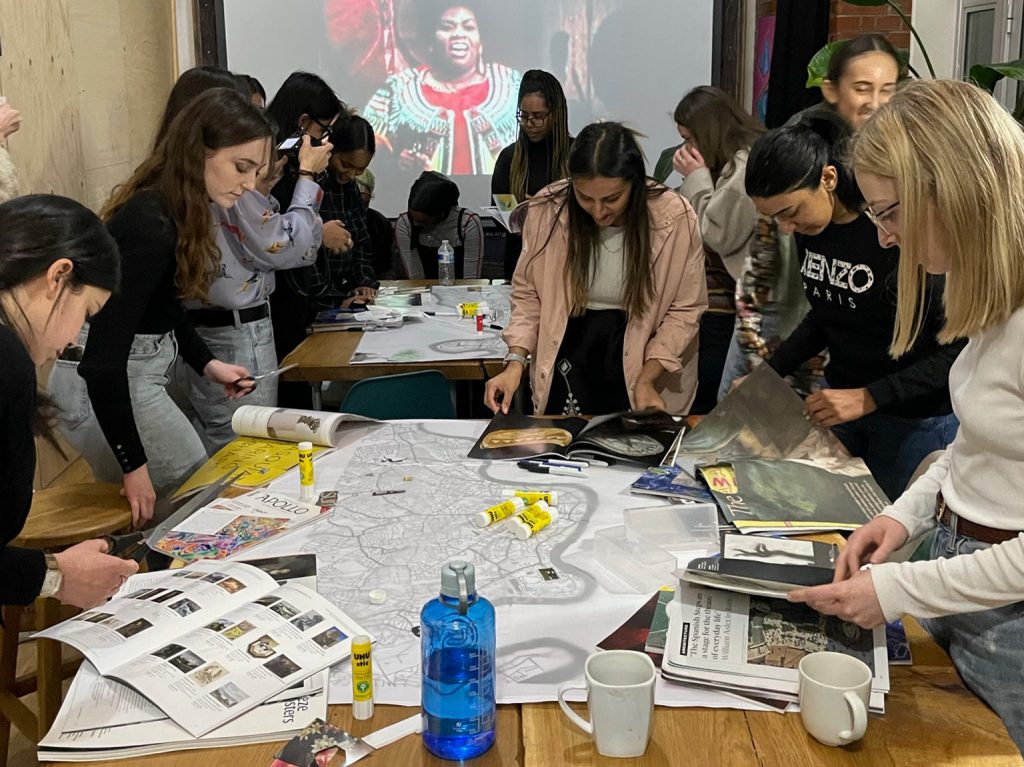 People standing around table with drawings, notes etc