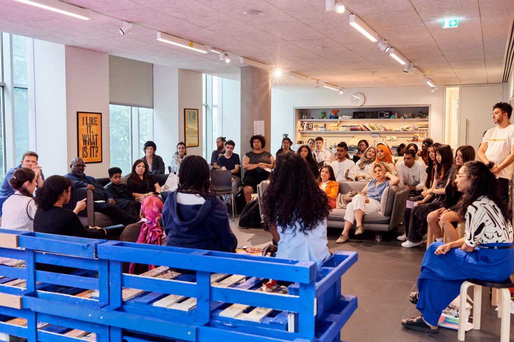Group of people gathered in a room around blue benches