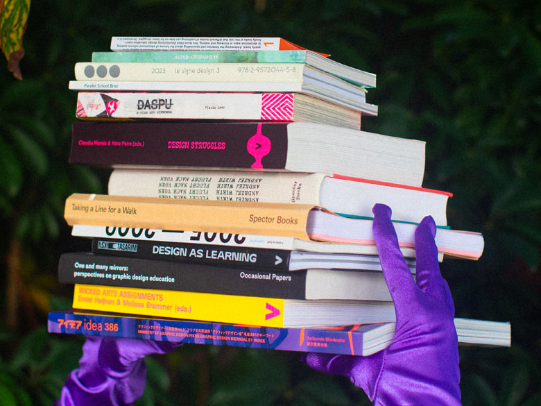 Pilo of books held by hands in purple gloves